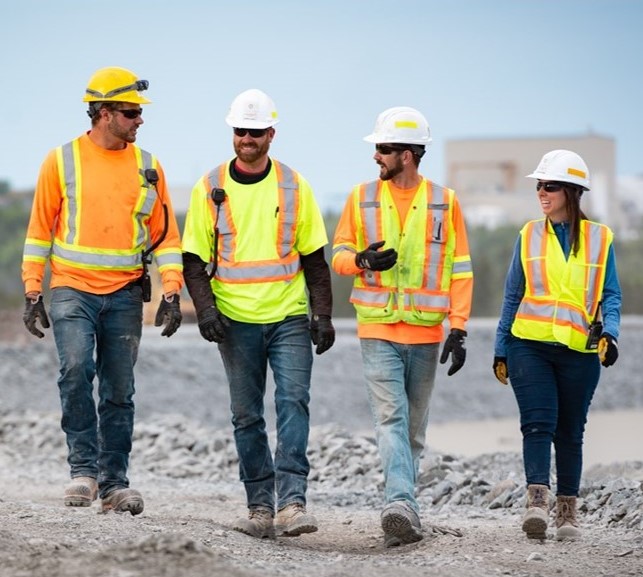 people walking wearing safety vests and hard hats